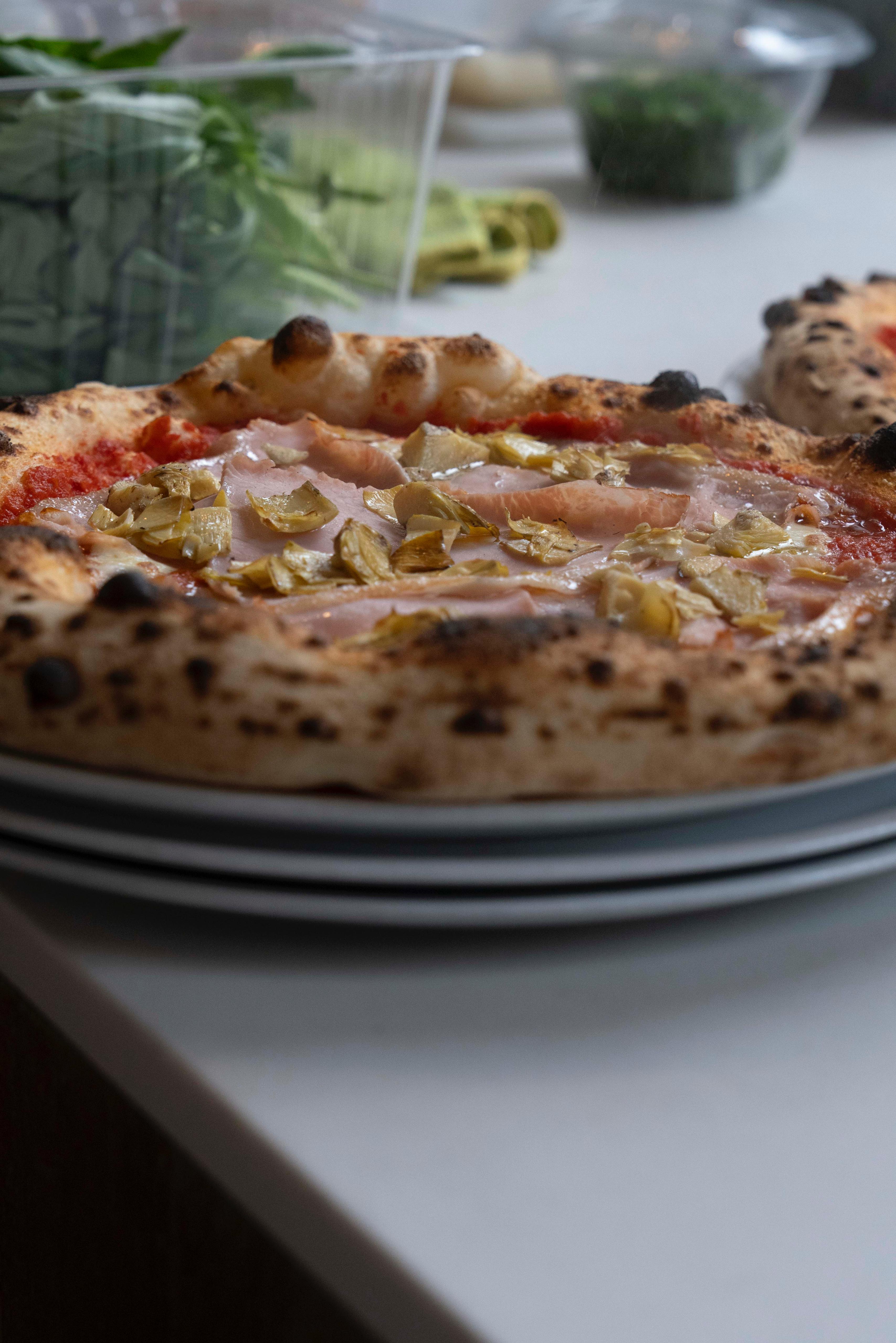 Detail van pizza met ham en artisjokken bij Kalura, Antwerpen