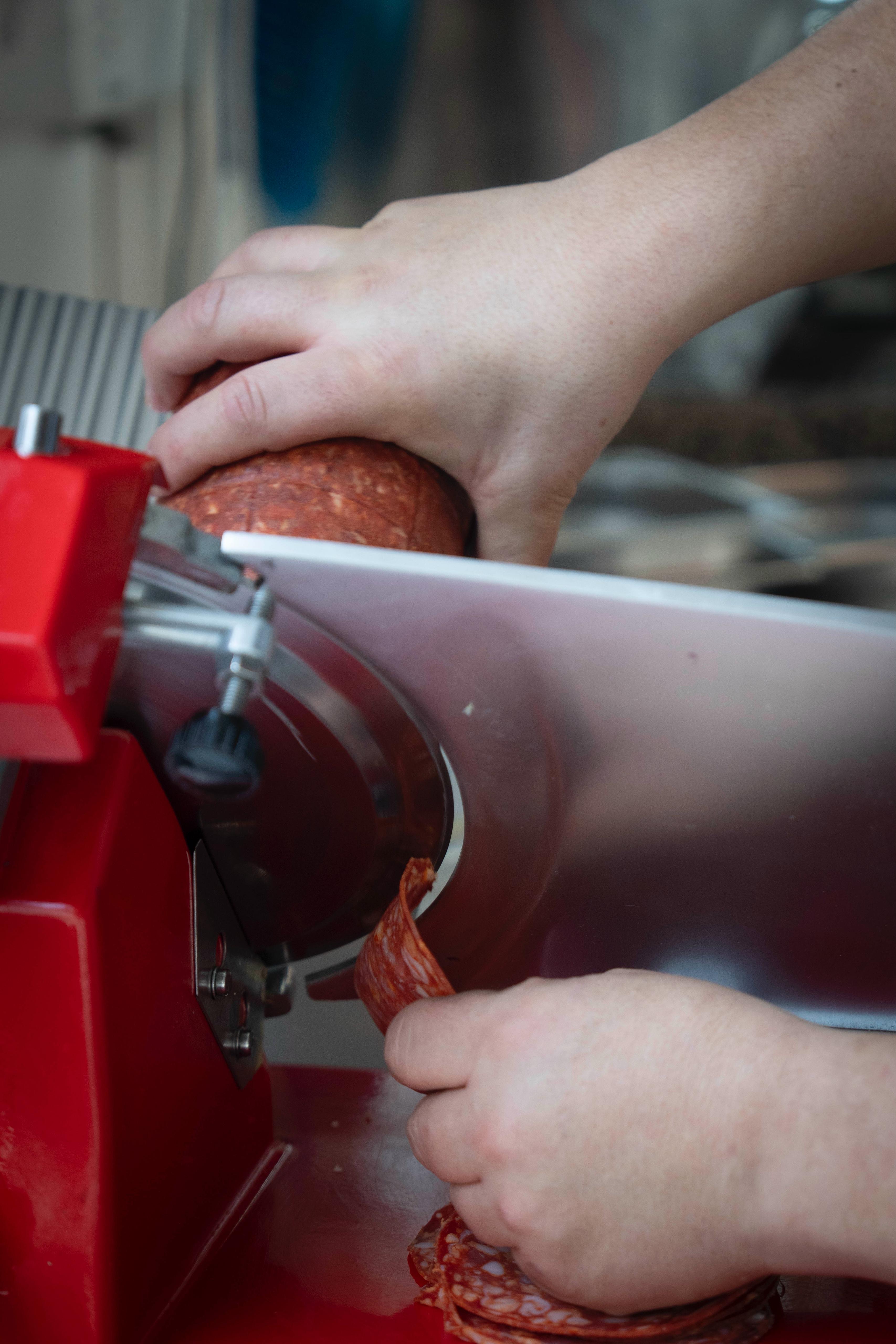 Salami snijden met een vleessnijmachine bij Kalura, Antwerpen
